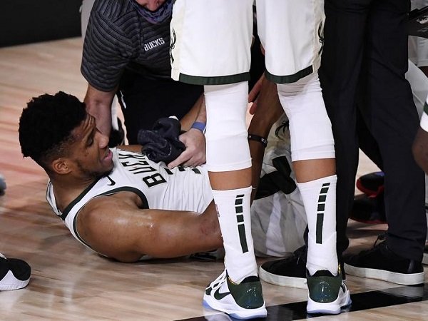 Giannis Antetokounmpo meringis kesakitan sambil memegangi engkelnya.