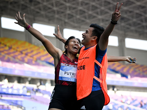 Peraih medali emas Ni Made Arianti Putri Ni (kiri) merayakan dengan pemandunya Bayu Aji Laksono setelah memenangkan final nomor lari 100m T12 putri di Asian Para Games ke-4 di Hangzhou. (Foto: Xinhua)