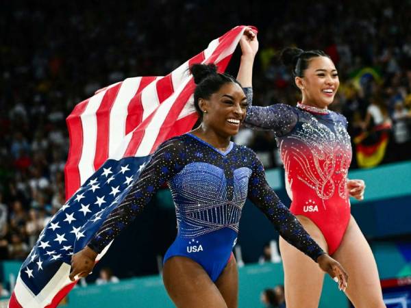 Simone Biles (kiri) dan Sunisa Lee merayakan sukses menyumbang medali emas dan perunggu untuk AS di nomor senam all-around putri Olimpiade Paris pada Kamis (1/8). (Foto: Yahoo Sports)