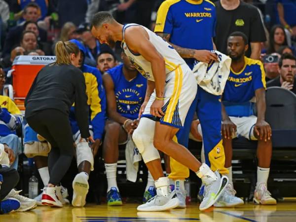 Steph Curry berjalan pincang di depan bangku Cadangan Warriors setelah mengalami keseleo pergelangan kaki kiri. (Foto: Mercury News)