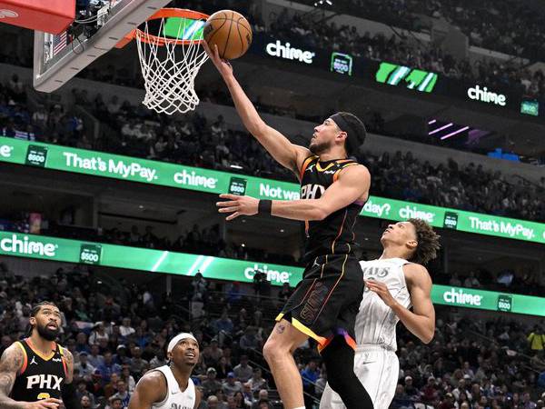 Devin Booker (tengah) mencetak 24 poin saat tim tamu Phoenix Suns mengalahkan Dallas Mavericks 125-116 pada hari Minggu (9/3) sore.