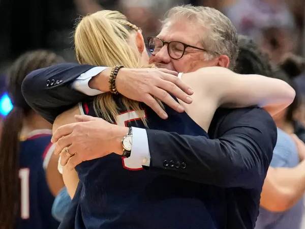 Pelatih UConn Geno Auriemma (kanan) memeluk salah satu bintangnya, Paige Bueckers, jelang akhir pertandingan melawan South Carolina. (Foto: AP)