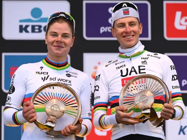 Tadej Pogacar (kanan) dan Lotte Kopecky berpose dengan trofi juara. (Foto: AFP)