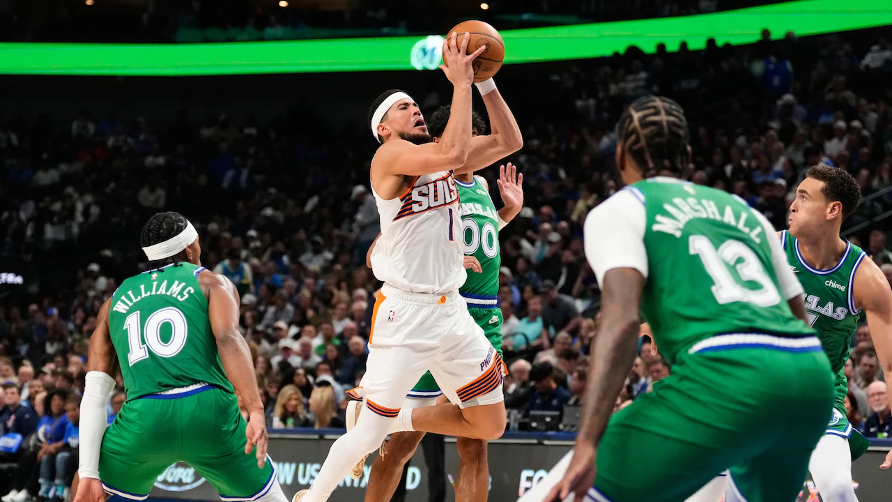 Devin Booker (tengah) mencetak 26 poin saat Phoenix Suns mengalahkan tuan rumah Dallas Mavericks dengan skor 123-114 pada Rabu (12/11) malam. (Foto: AP)