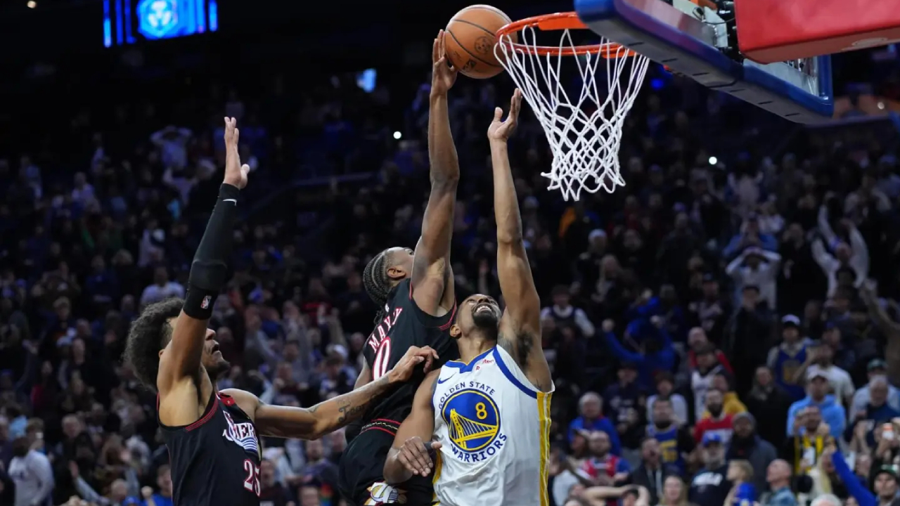Tyrese Maxey (tengah) memblok upaya tembakan De’Anthony Melton untuk memastikan kemenangan Philadelphia 76ers 99-98 atas tim tamu Golden State Warriors pada Kamis (4/12) malam. (Foto: AP)