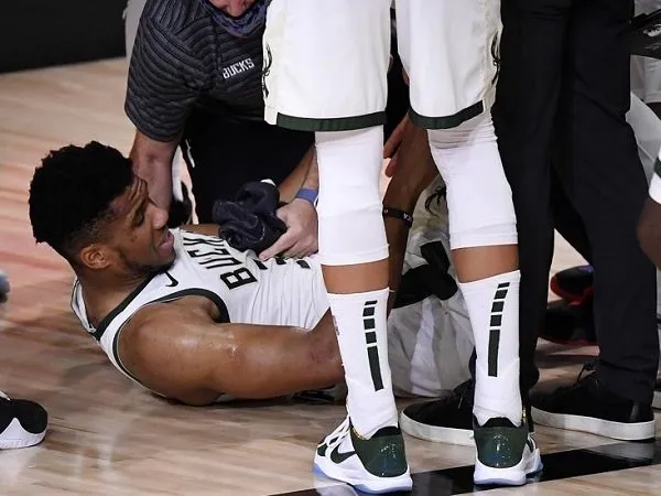 Giannis Antetokounmpo meringis kesakitan sambil memegangi engkelnya.