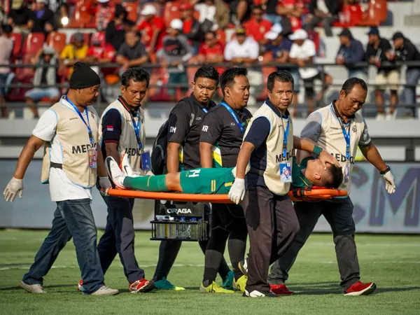 Gelandang Persebaya Surabaya, Sho Yamamoto harus ditandu keluar usai berbenturan dengan pemain Bali United