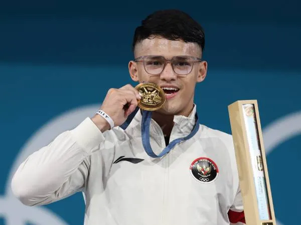 Lifter Rizki Juniansyah berpose dengan berpose dengan medali emasnya setelah memenangi kelas 73kg putra di Olimpiade Paris pada Kamis (8/8). (Foto: Xinhua)