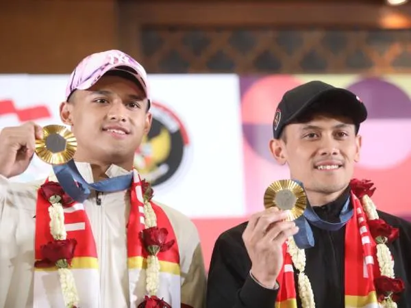 Veddriq Leonardo (kanan) dan Rizki Juniansyah memamerkan medali emas Olimpiade mereka saat disambut pulang pada Selasa (13/8) malam. (Foto: Menpora)