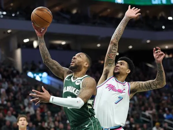 Damian Lillard (kiri) mencetak 29 poin saat Milwaukee Bucks meraih kemenangan 125-96 atas tim tamu Miami Heat pada Kamis (23/1) malam. (Foto: AP)