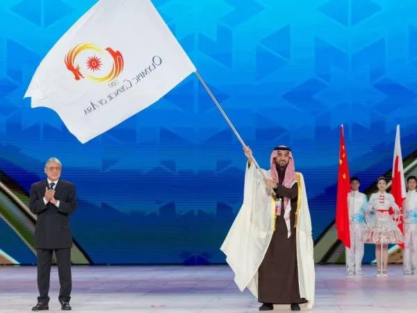 Kepala kontingen Kerajaan Arab Saudi, Pangeran Abdulaziz bin Turki Al-Faisal, mengibarkan bendera Dewan Olimpiade Asia, sebagai simbol penyerahan tugas tuan rumah Asian Winter Games 2029. (Foto: Inside The Games)