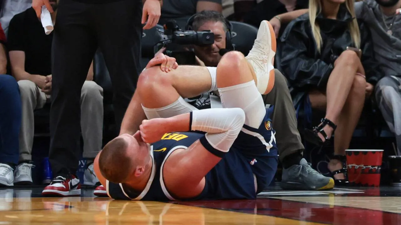 Nikola Jokic tampak terjatuh ke lantai sambil memegangi lututnya. (Foto: AP)