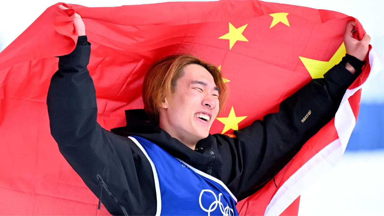 Su Yiming melakukan selebrasi sambil mengibarkan bendera China setelah memenangi nomor slopestyle putra di Olimpiade Milan-Cortina. (Foto: AP)