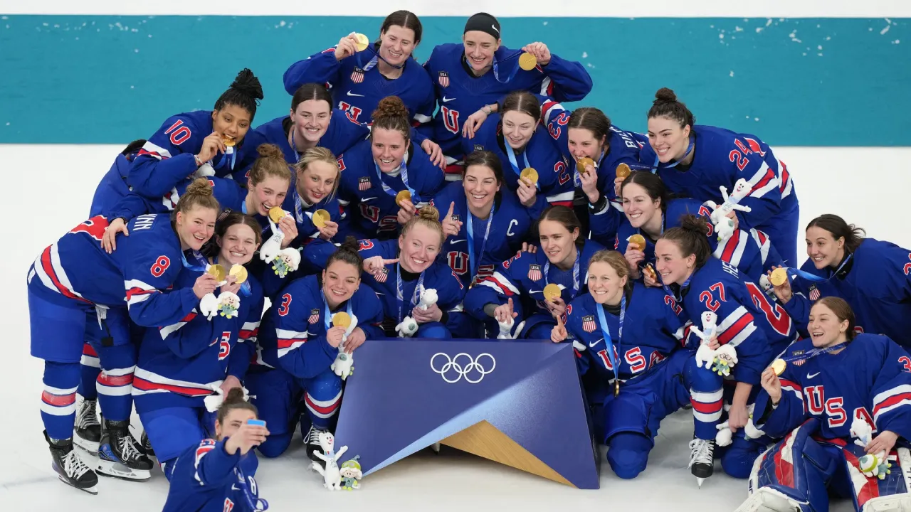 Para pemain hoki es putri AS melakukan swafoto sambil memamerkan medali emas mereka setelah upacara pengalungan medali. (Foto: AP)