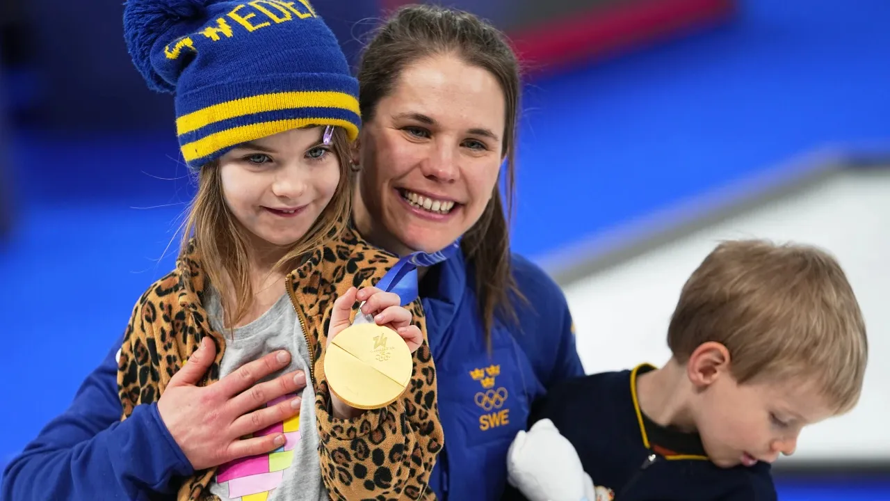Anna Hasselborg menyerahkan medali emasnya kepada kedua anaknya untuk dimainkan sesaat setelah upacara penyerahan medali curling putri. (Foto: AP)