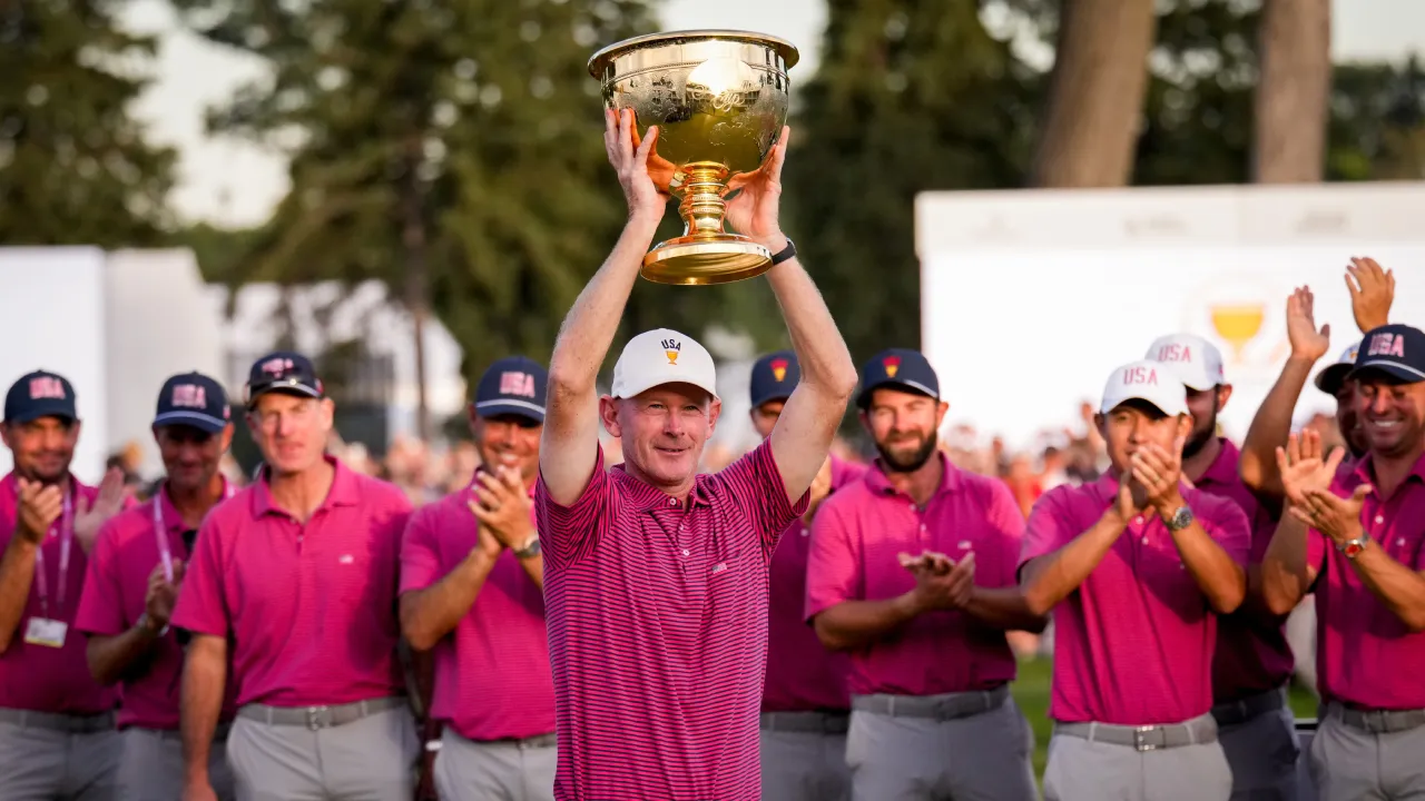 Kapten AS Brandt Snedeker mengangkat trofi Presidents Cup setelah timnya memastikan kemenangan di hari terakhir, Minggu (27/9)